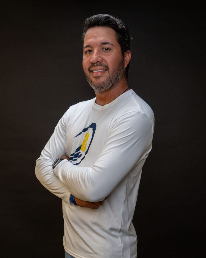 Smiling man with crossed arms, dark backdrop